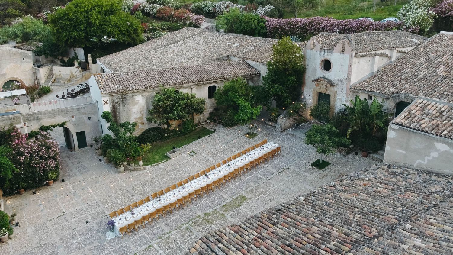Stone buildings and terraces overlooking a Mediterranean coastline with clear blue waters.