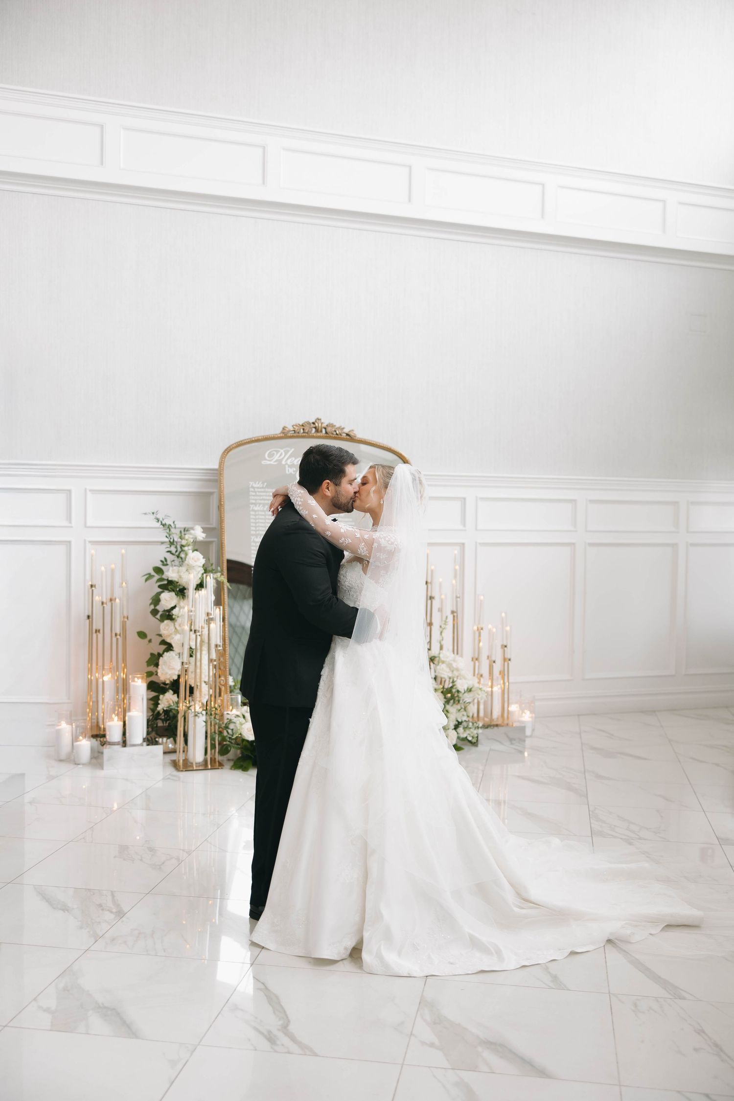 Romantic wedding portraits in a bright white room with vintage mirror and floral accents.