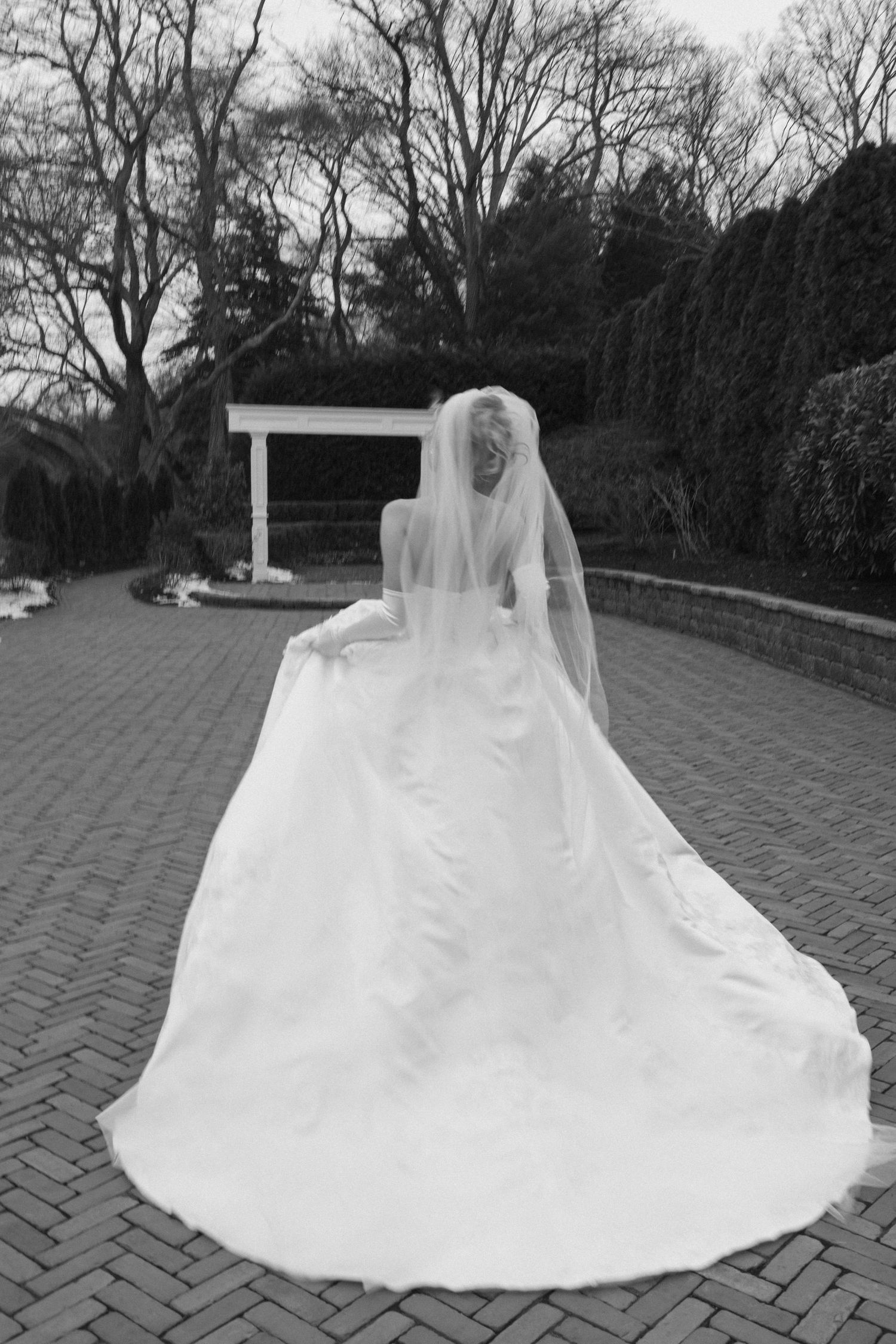 White wedding dress train spreads beautifully across brick paving stones.