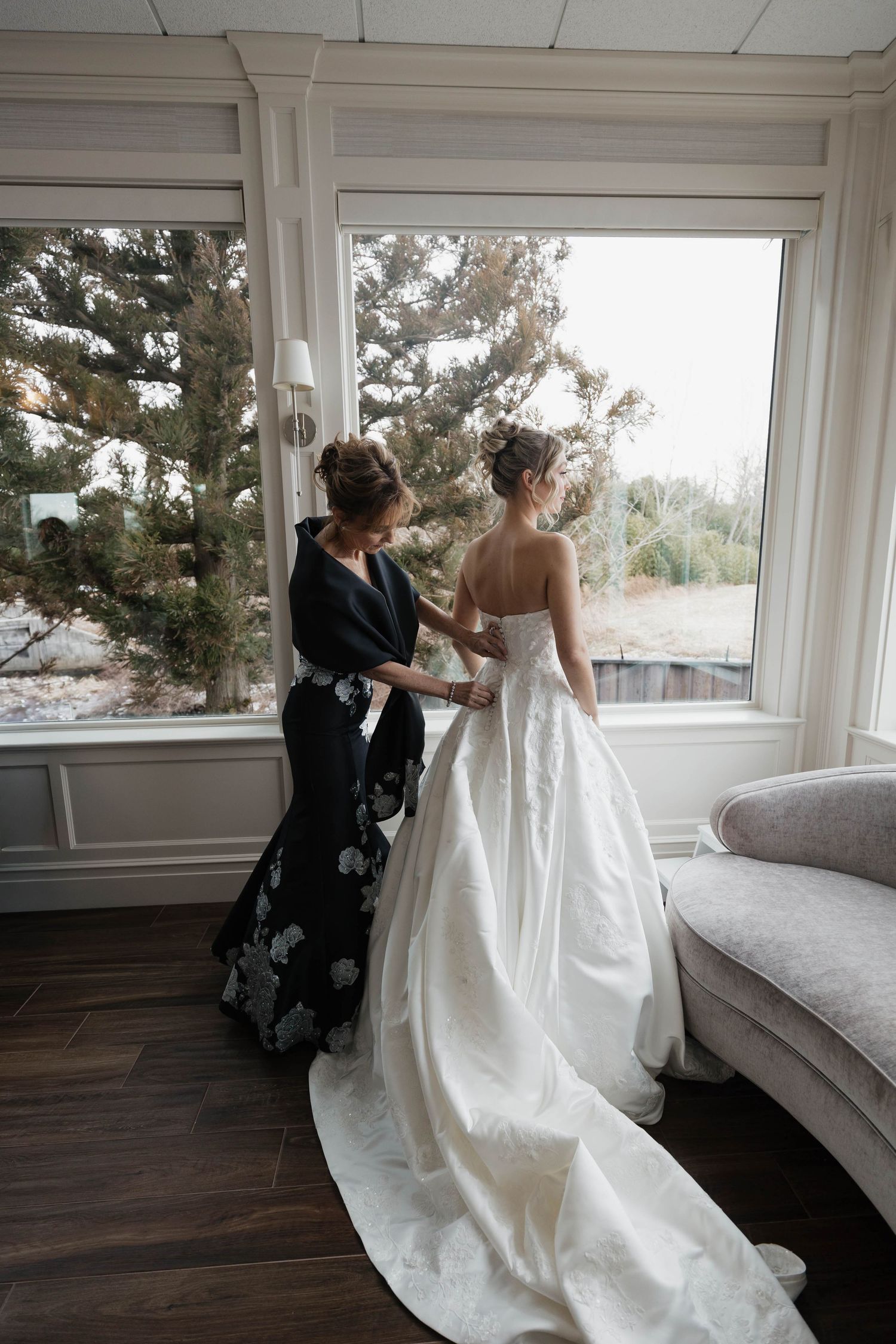 Classic white wedding gown with long train photographed against window backdrop.