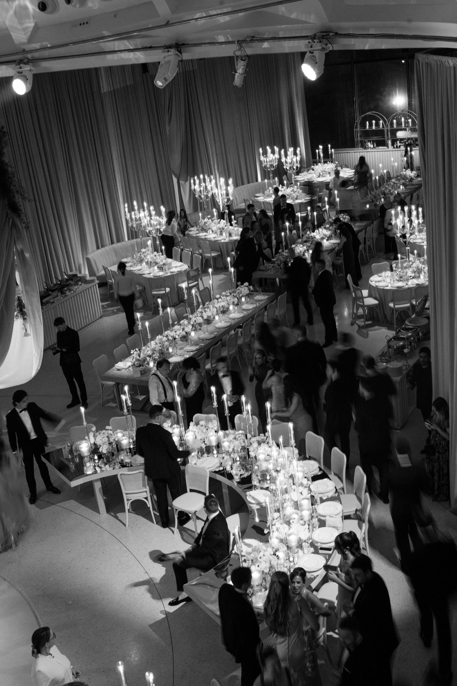 Elegant wedding reception venue with candlelit tables and guests mingling in formal attire.