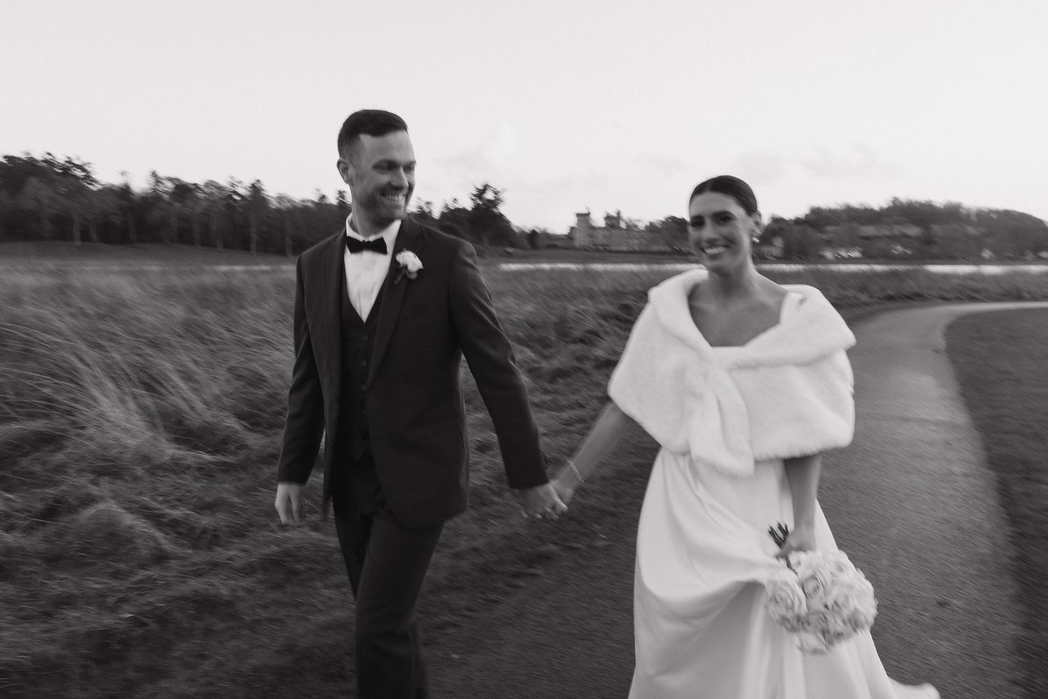 Black and white sequence of a couple walking along a coastal path on their wedding day.