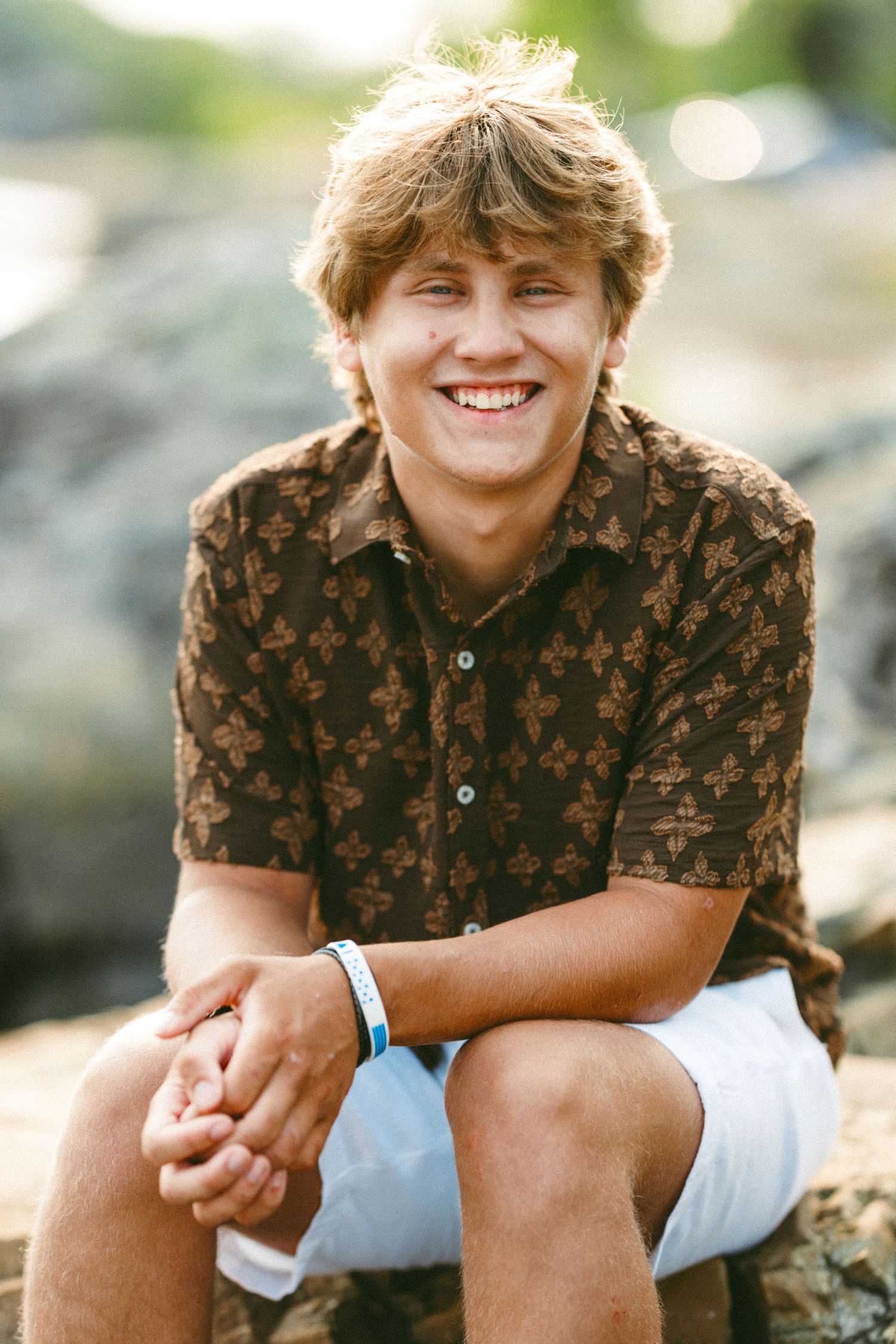 Casual portraits on rocks showing person wearing brown patterned shirt.