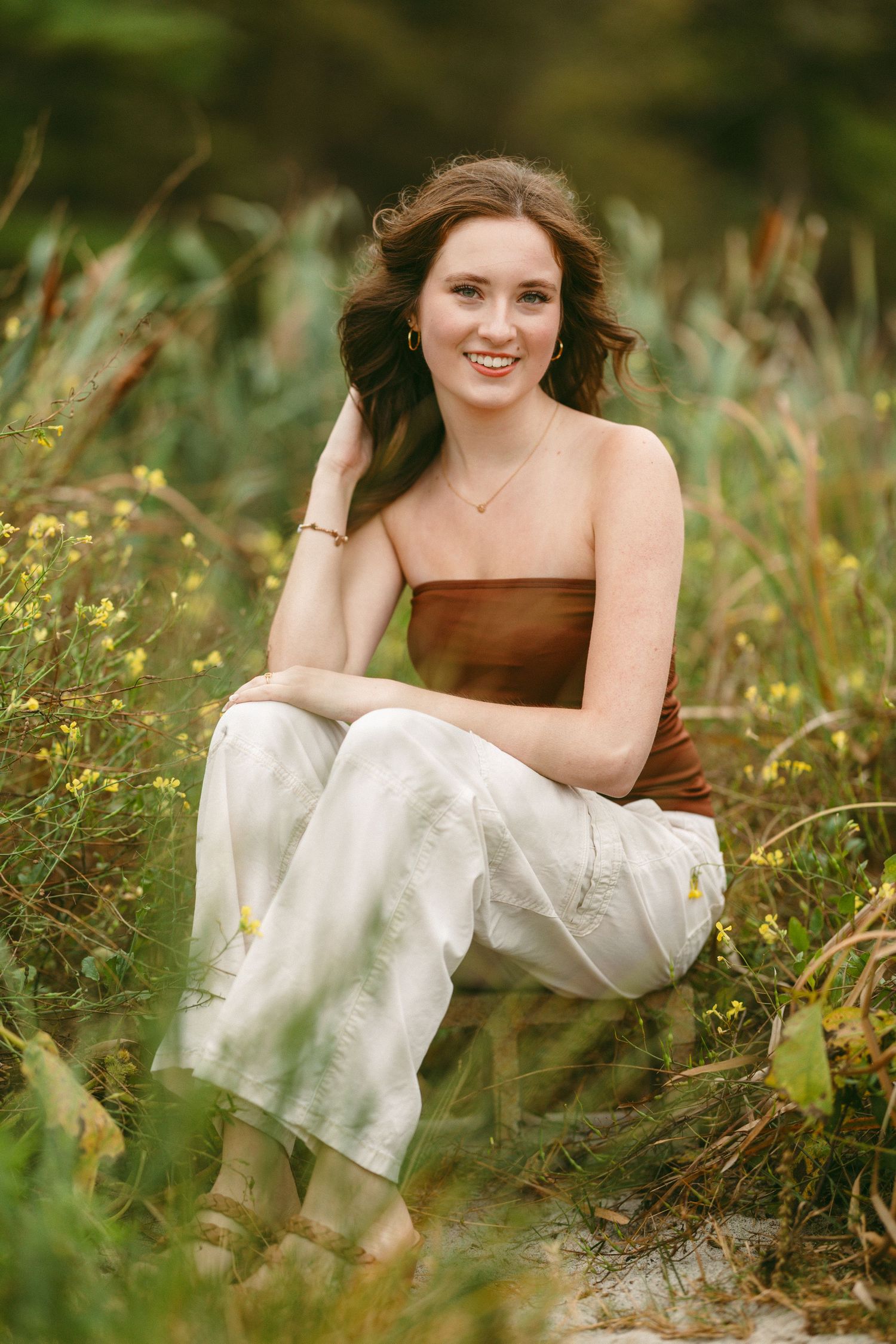 A brown and white dress creates contrast against lush green wildflowers in a natural outdoor setting.