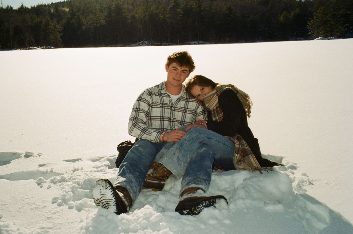 A couple enjoys winter fun while sledding down a snowy hill in sequence of action shots.