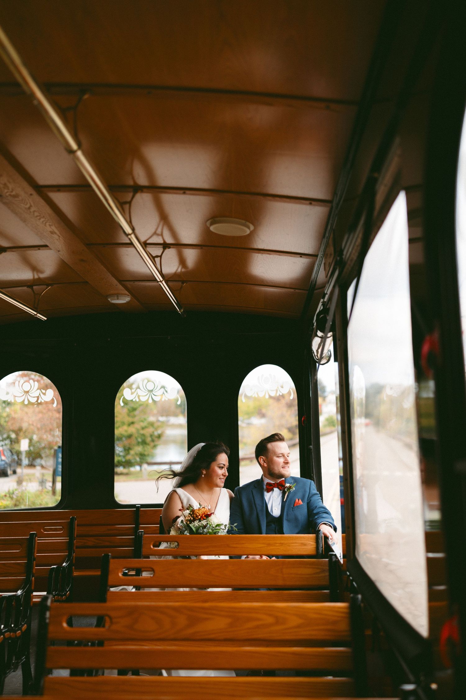 Wedding guests seated on wooden pews inside a rustic train car during a unique ceremony.