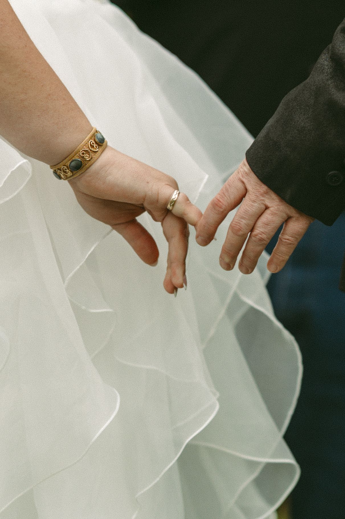 Close up of hands adjusting the delicate folds of a white wedding dress.