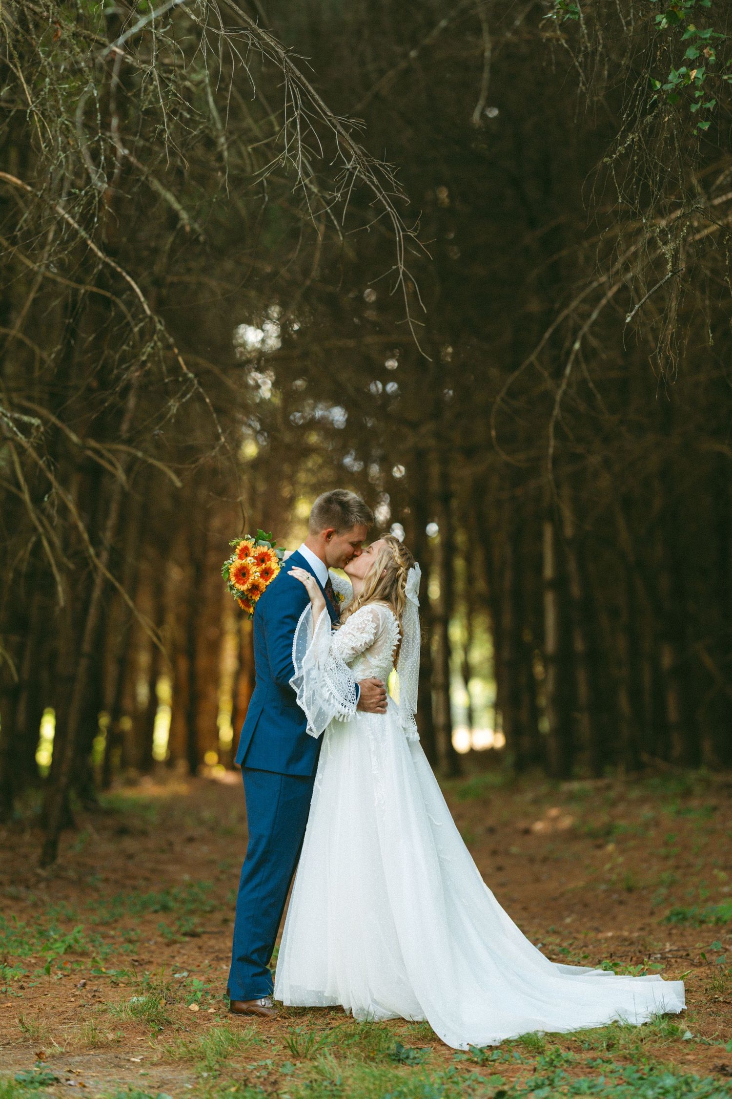 A romantic wedding photoshoot in a wooded forest setting at golden hour.