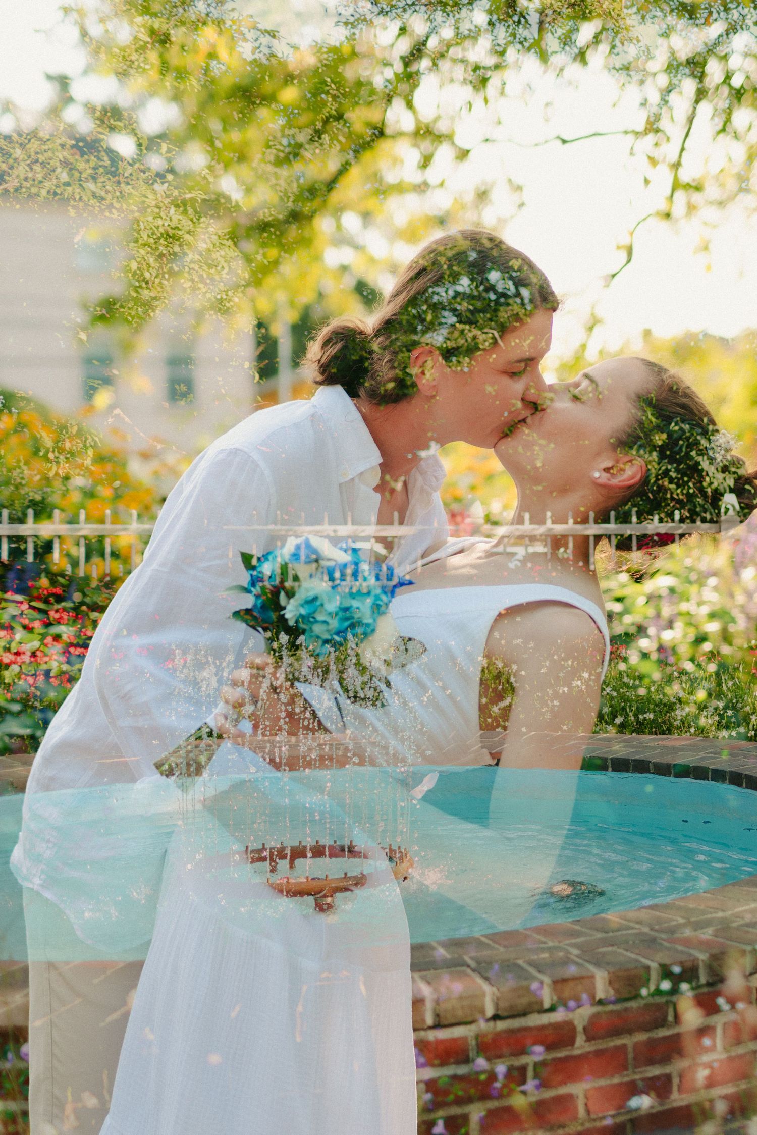 A couple shares a tender moment in a garden setting with sunlit foliage.