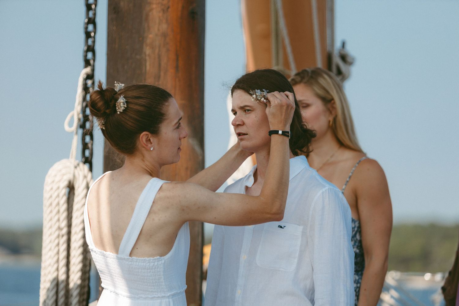 Wedding celebration on a wooden pier with guests in white attire.