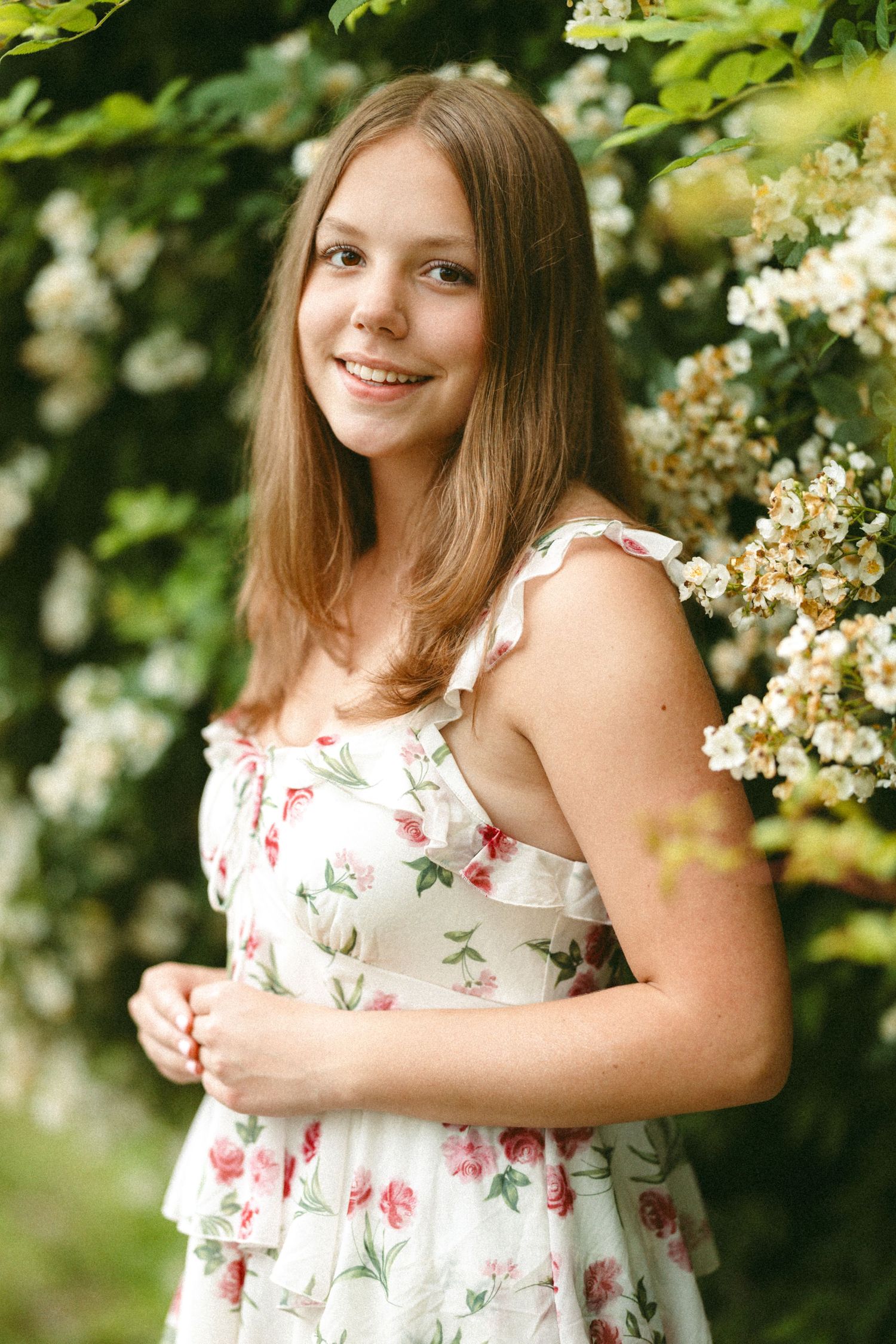 Garden portraits featuring someone in a floral sundress among white flowering bushes.