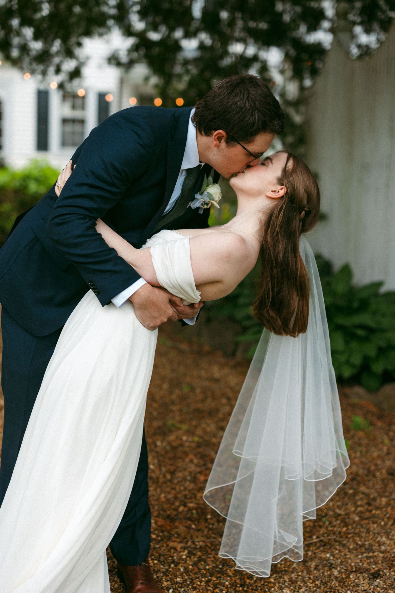Romantic wedding photos showing a couple in a dramatic dip kiss pose under trees.