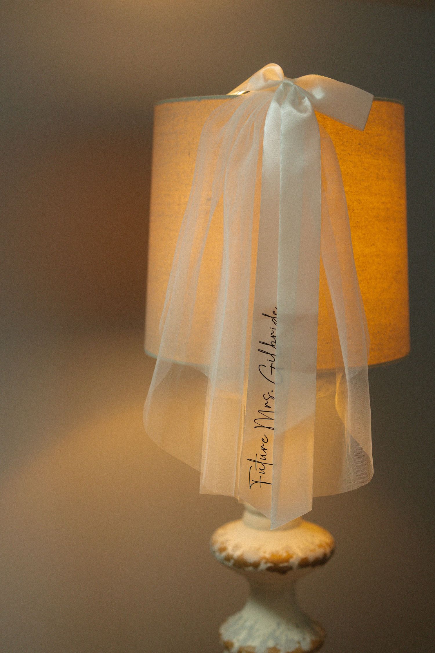 Bridal veil reading Future Mrs. Gilbride draped over a glowing table lamp with white bow.