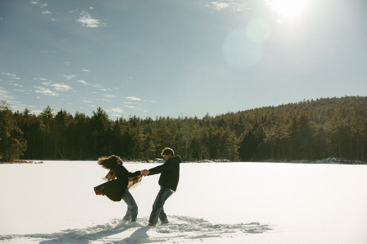 Snow-covered winter landscape with silhouettes of couple in the distance.
