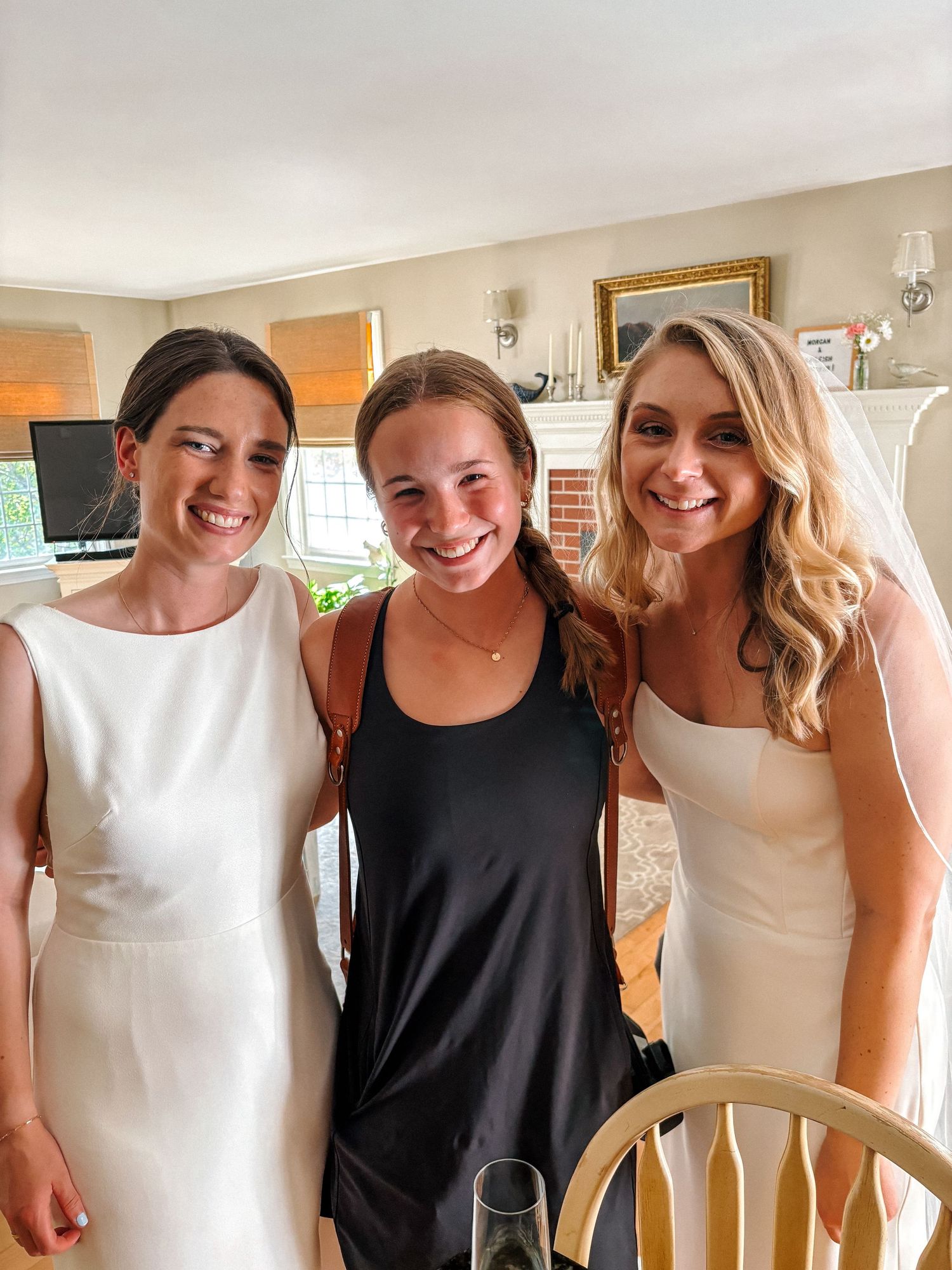 A group of women in alternating black and white sleeveless dresses stand together smiling at a social gathering.