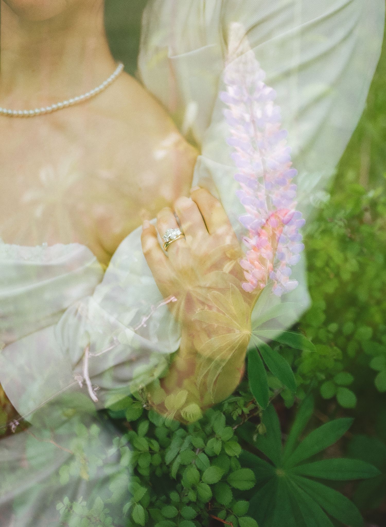 Dreamy double exposure of bride in white gown with pearl necklace and diamond ring overlaid with pink lupine flowers.
