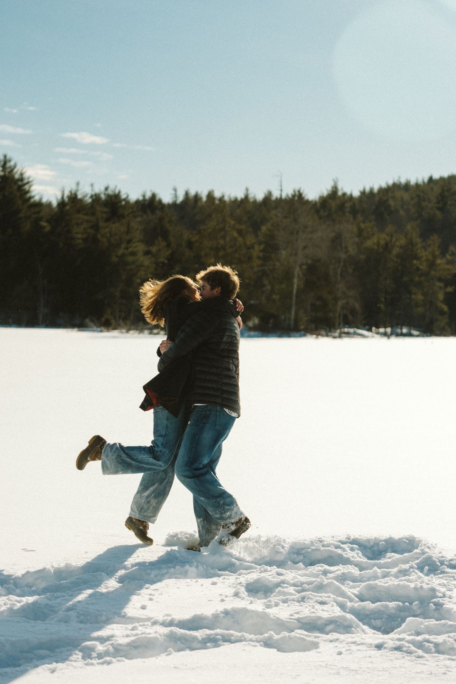 A sequence of action shots shows someone running and jumping through deep snow in a winter forest landscape.