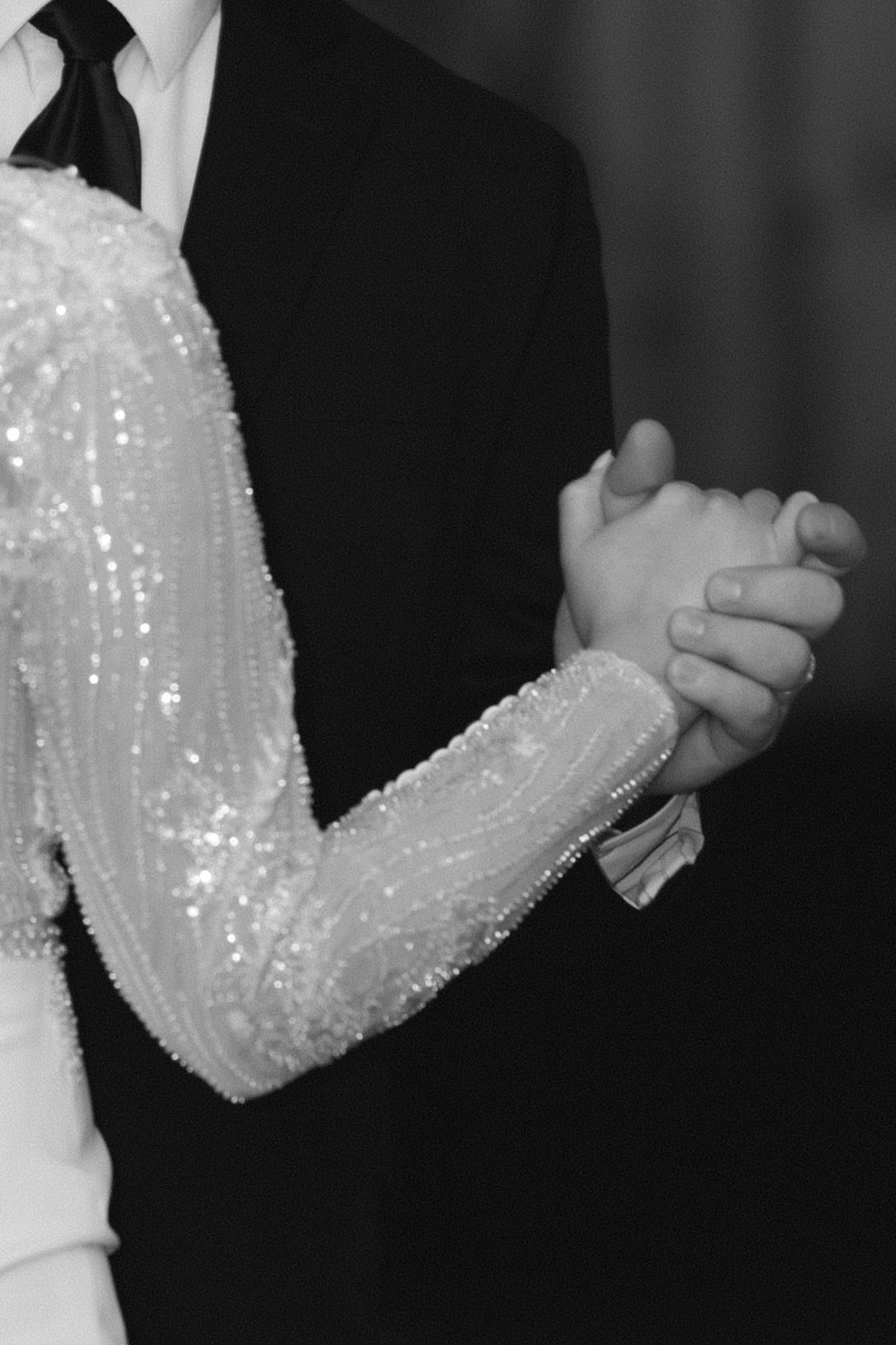 Close-up shots of a couple's hands during a wedding dance, with the bride wearing a sparkly white sequined sleeve.