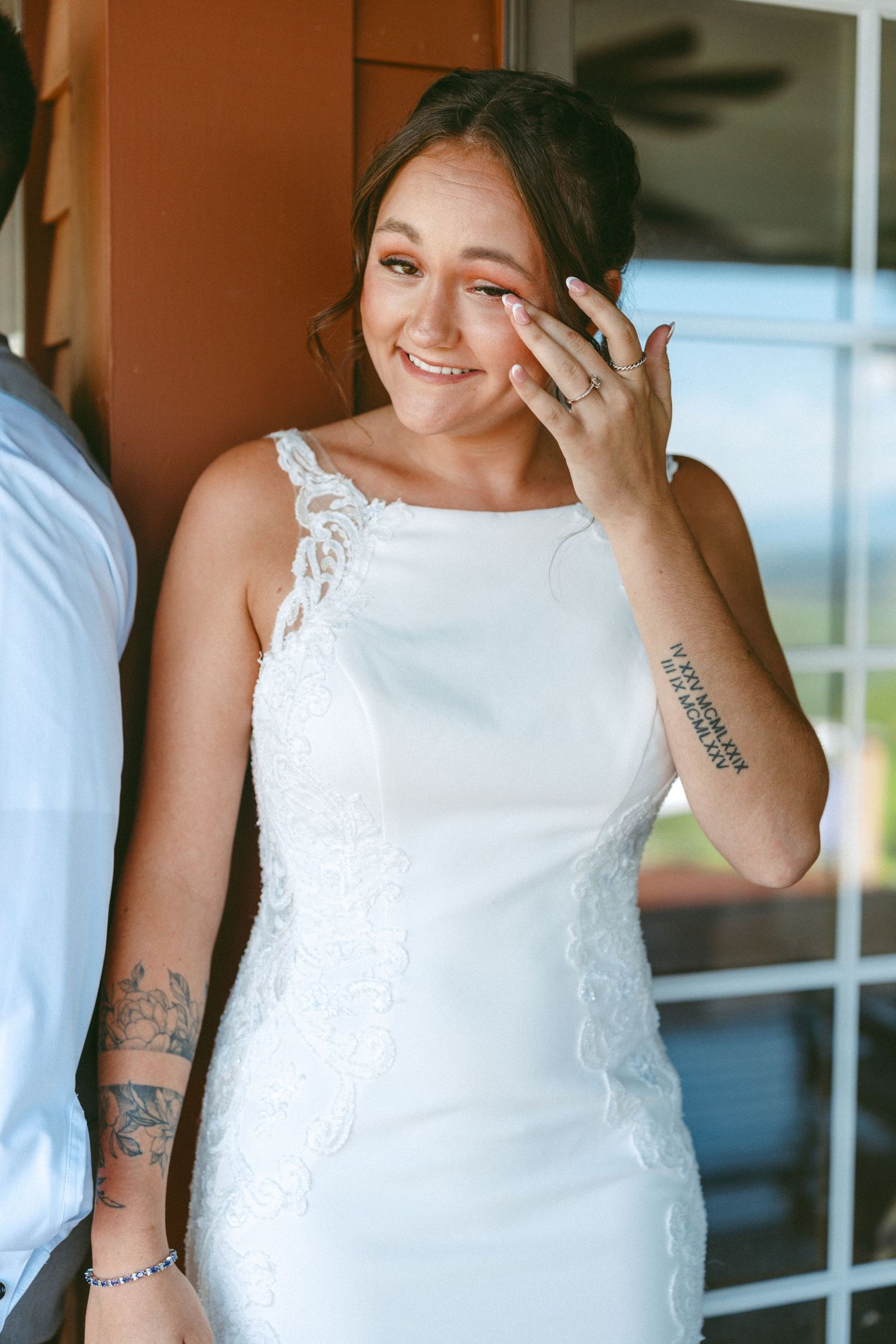 A candid moment of a bride in a white lace dress showing emotion.