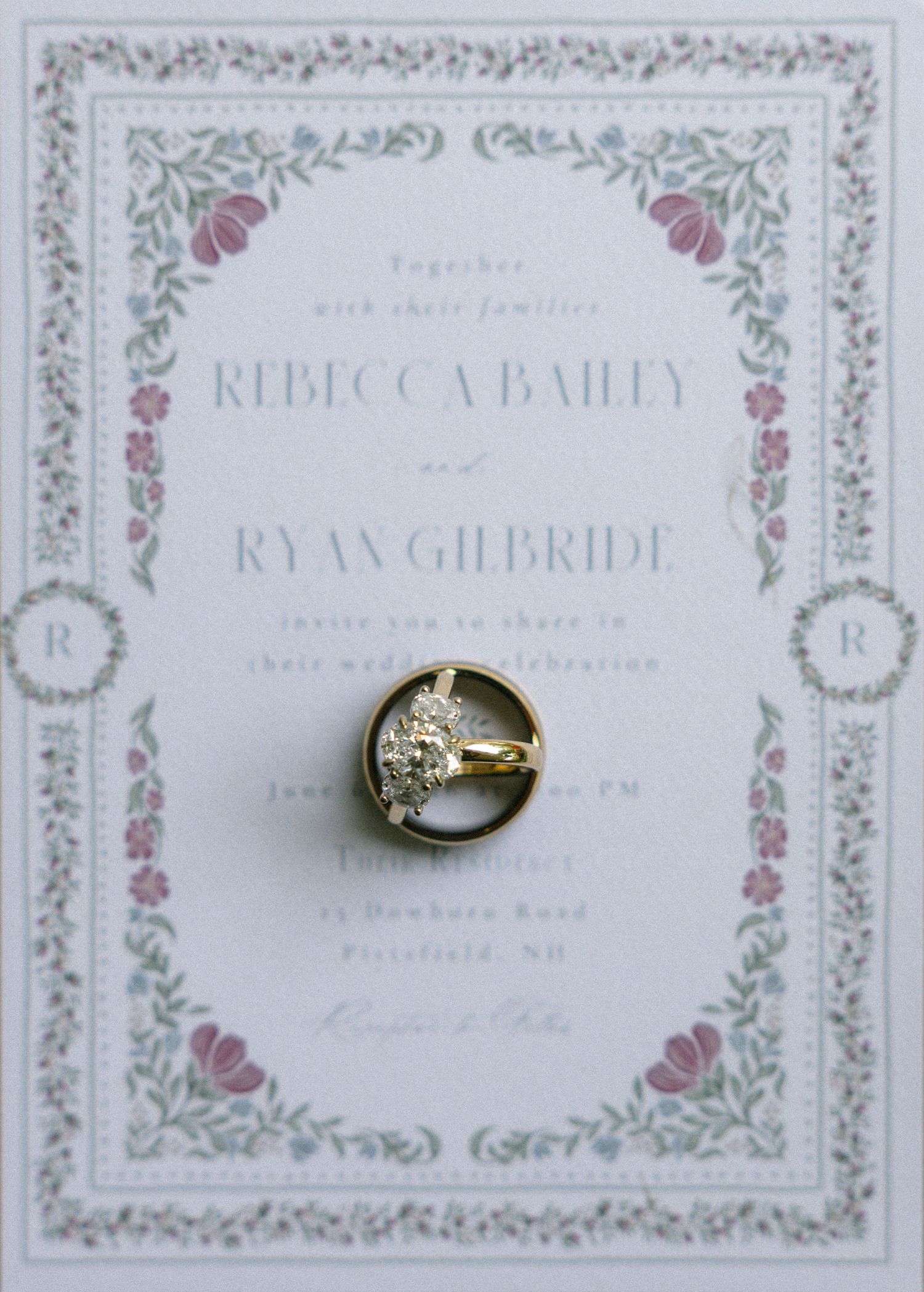 Wedding invitation for Rebecca Bailey and Ryan Gilbride with floral border and diamond engagement ring resting on top.
