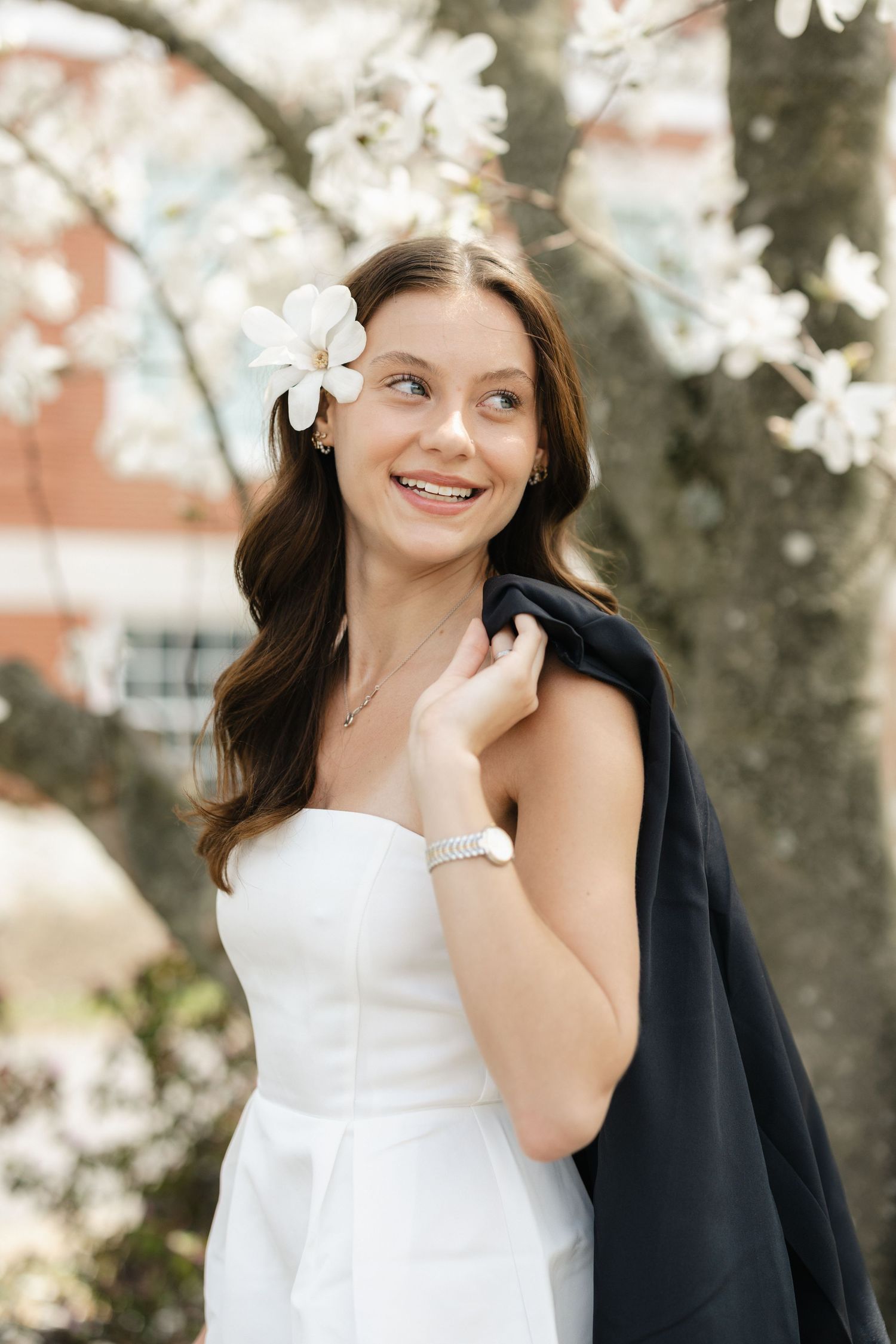 Spring graduate session featuring cherry blossoms and elegant white dress.