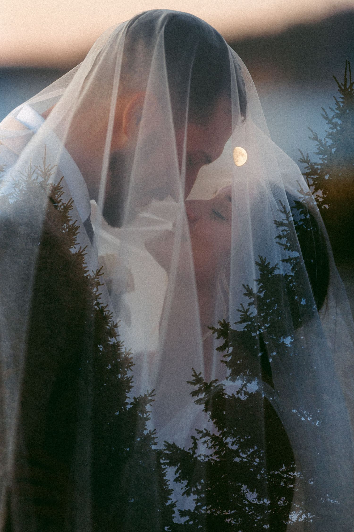 Artistic wedding photos through flowing white veil at sunset.