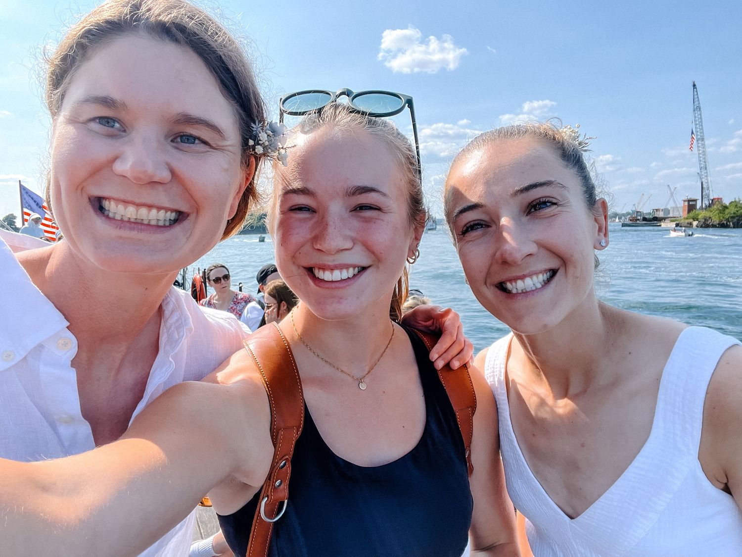 Group enjoying a sunny day on a boat with blue water and clear skies in the background.