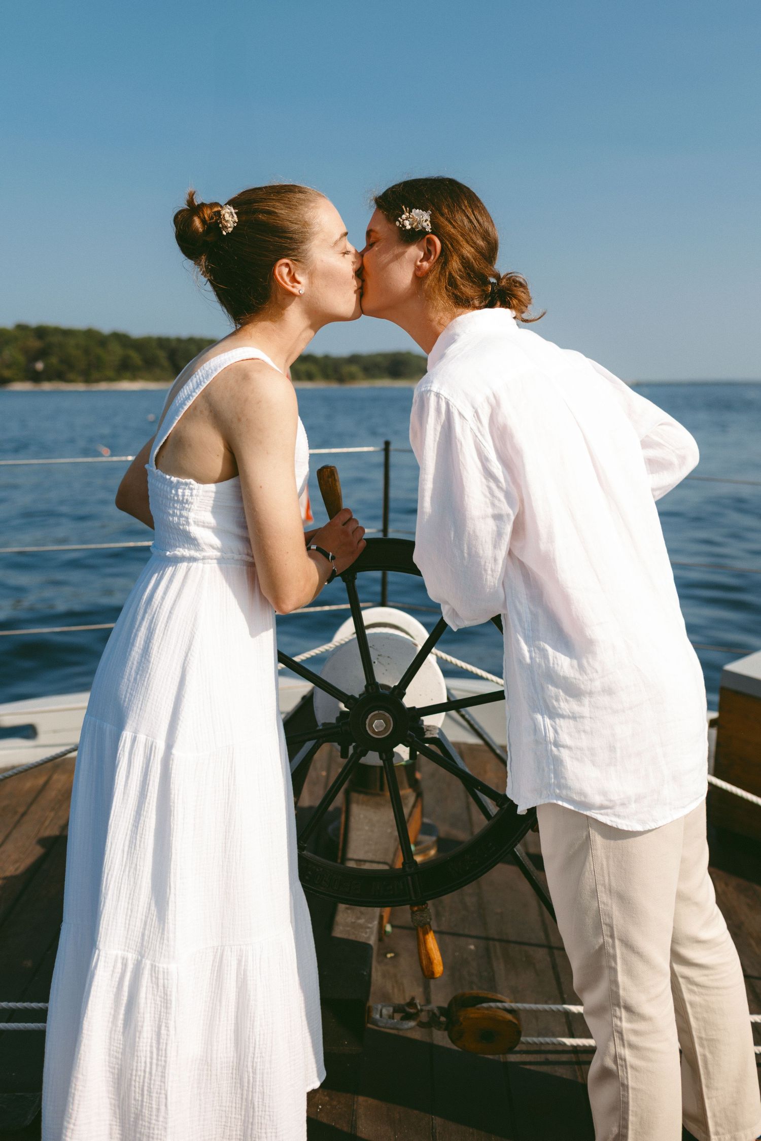 Couple sharing a romantic moment at the helm of a boat with ocean in background.
