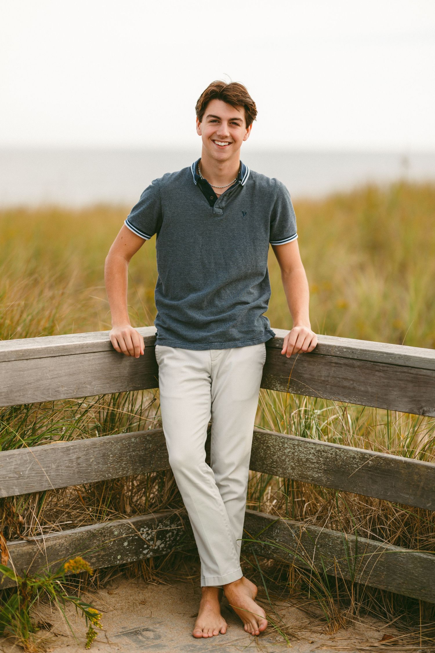 Casual summer portrait on a wooden fence overlooking a grassy field.