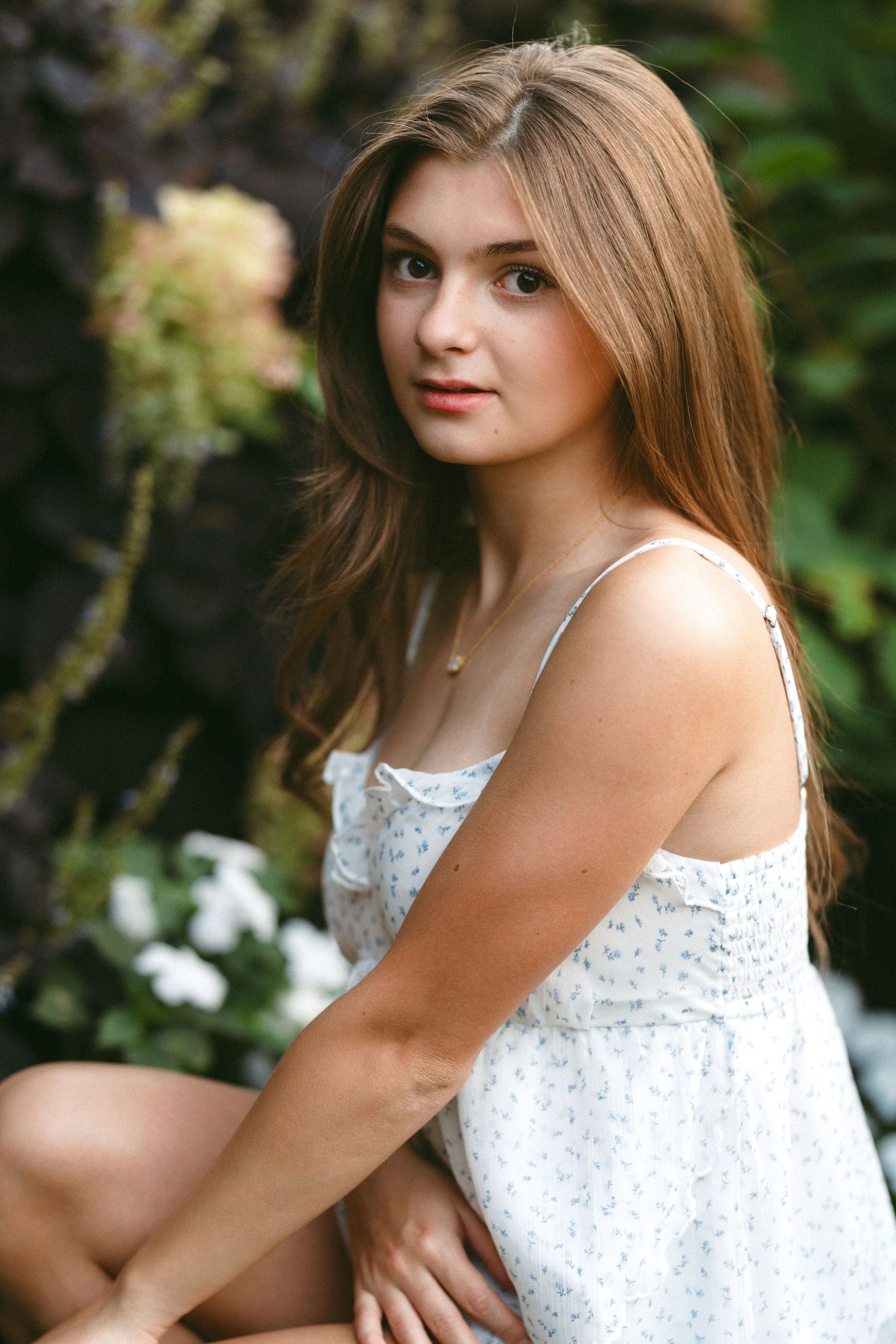 Portrait series featuring someone in a white lace top posing against greenery and foliage.