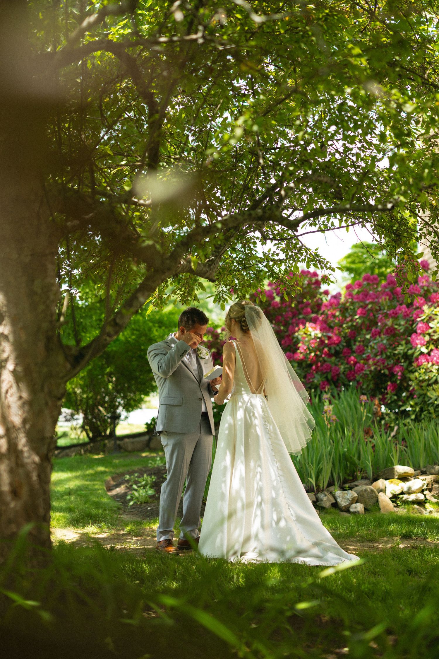Bride and groom share romantic moment in lush garden with blooming flowers on wedding day.