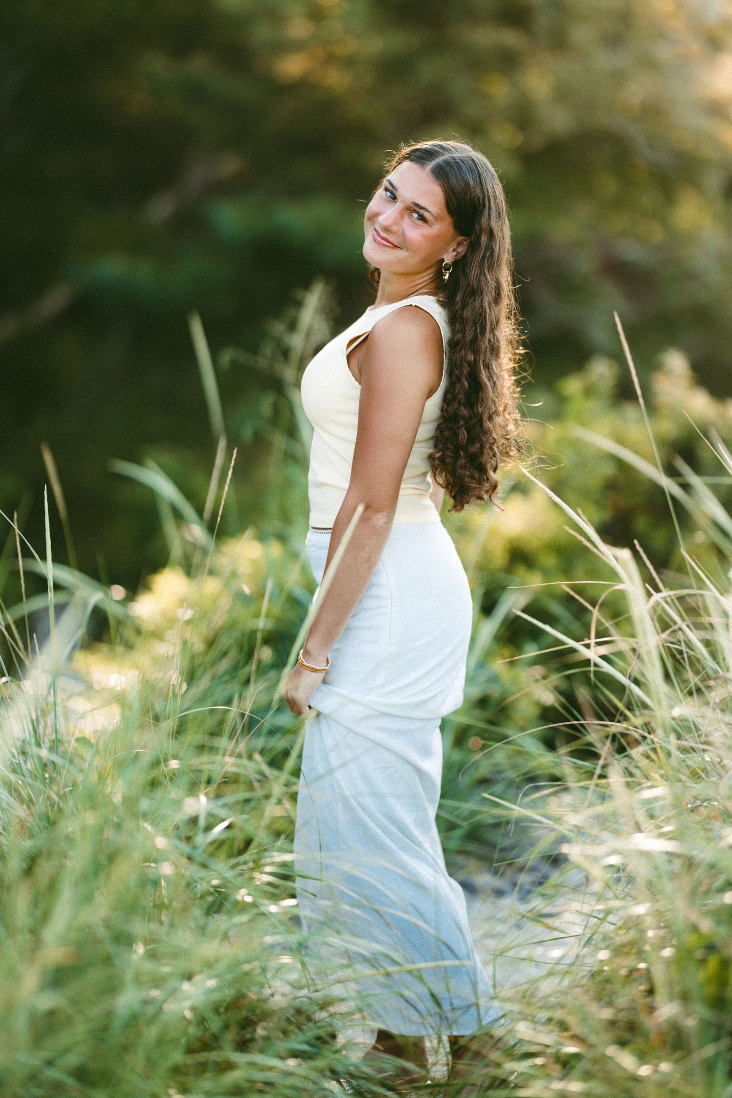 Summer portrait series with someone in a white dress posing among tall grass and natural light.