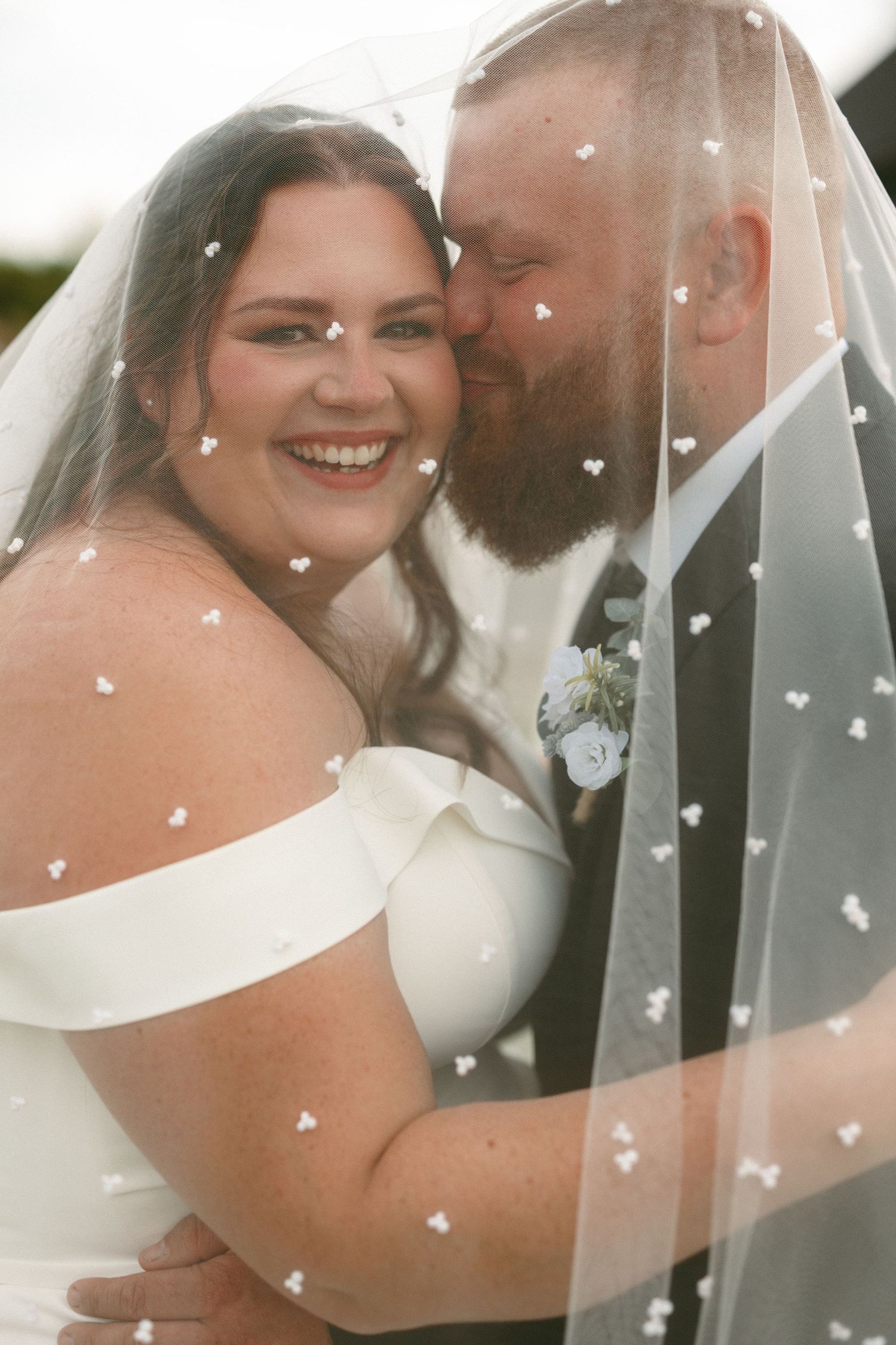 Wedding portraits through a delicate veil with heart-shaped confetti overlay.