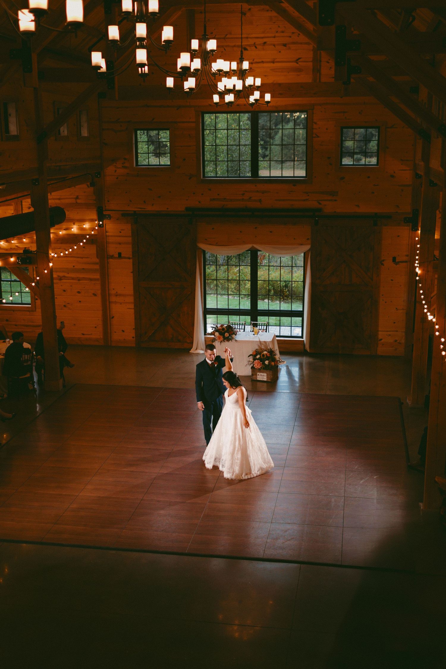 A romantic wedding reception venue with string lights illuminating a rustic wooden interior.
