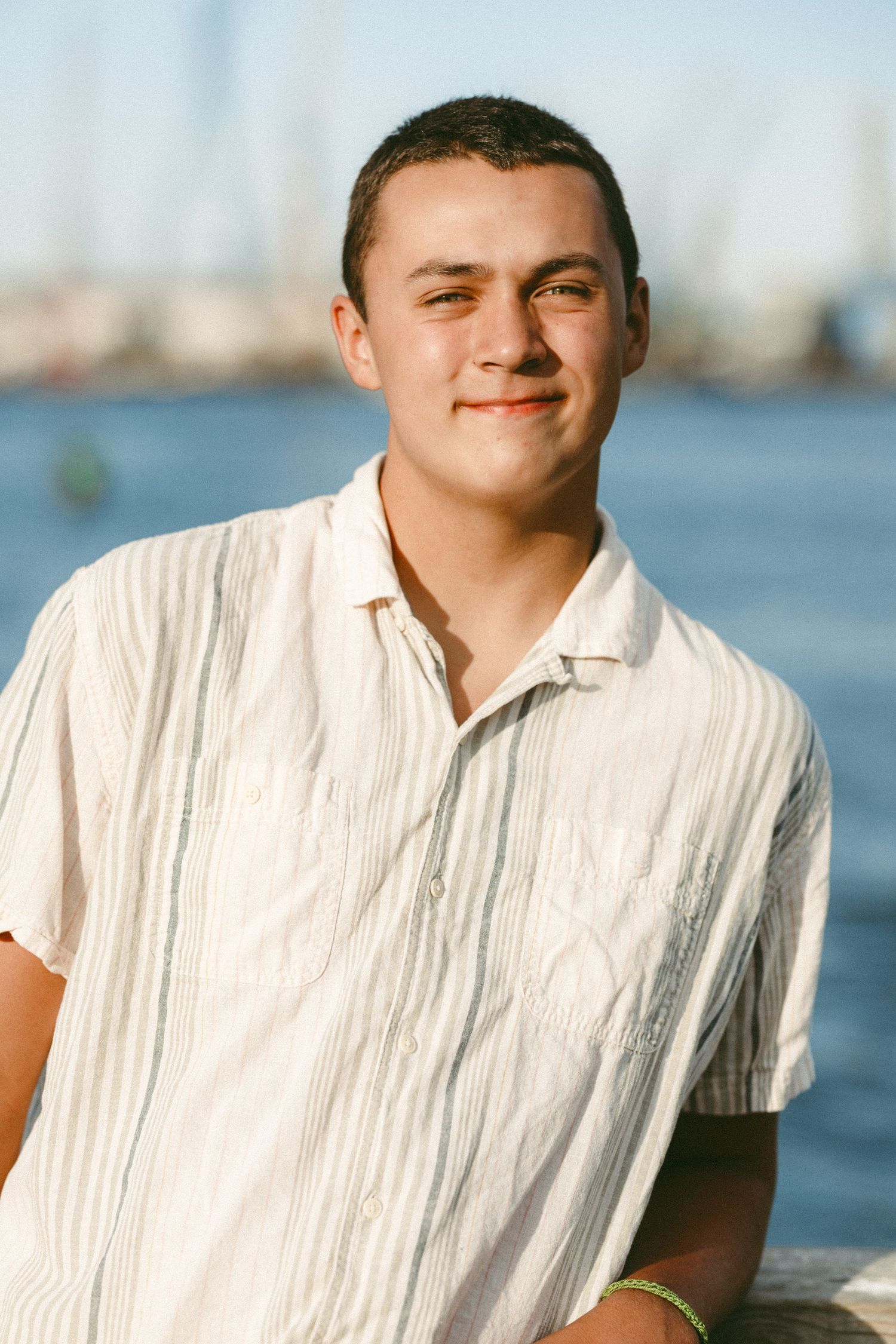 Waterfront portrait with white shirt against blue ocean background.