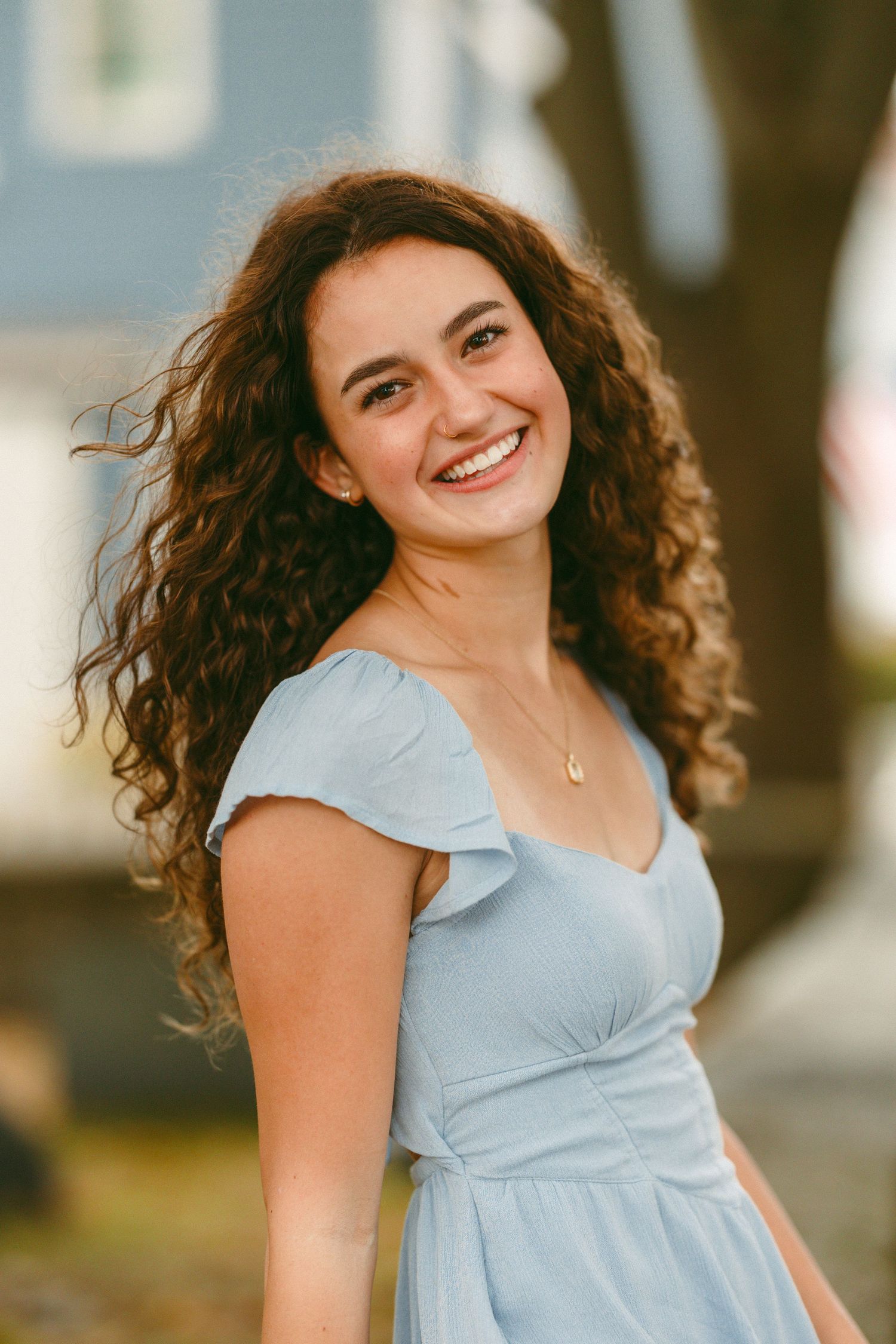 Joyful poses in a light blue dress create casual summer portraits outdoors.