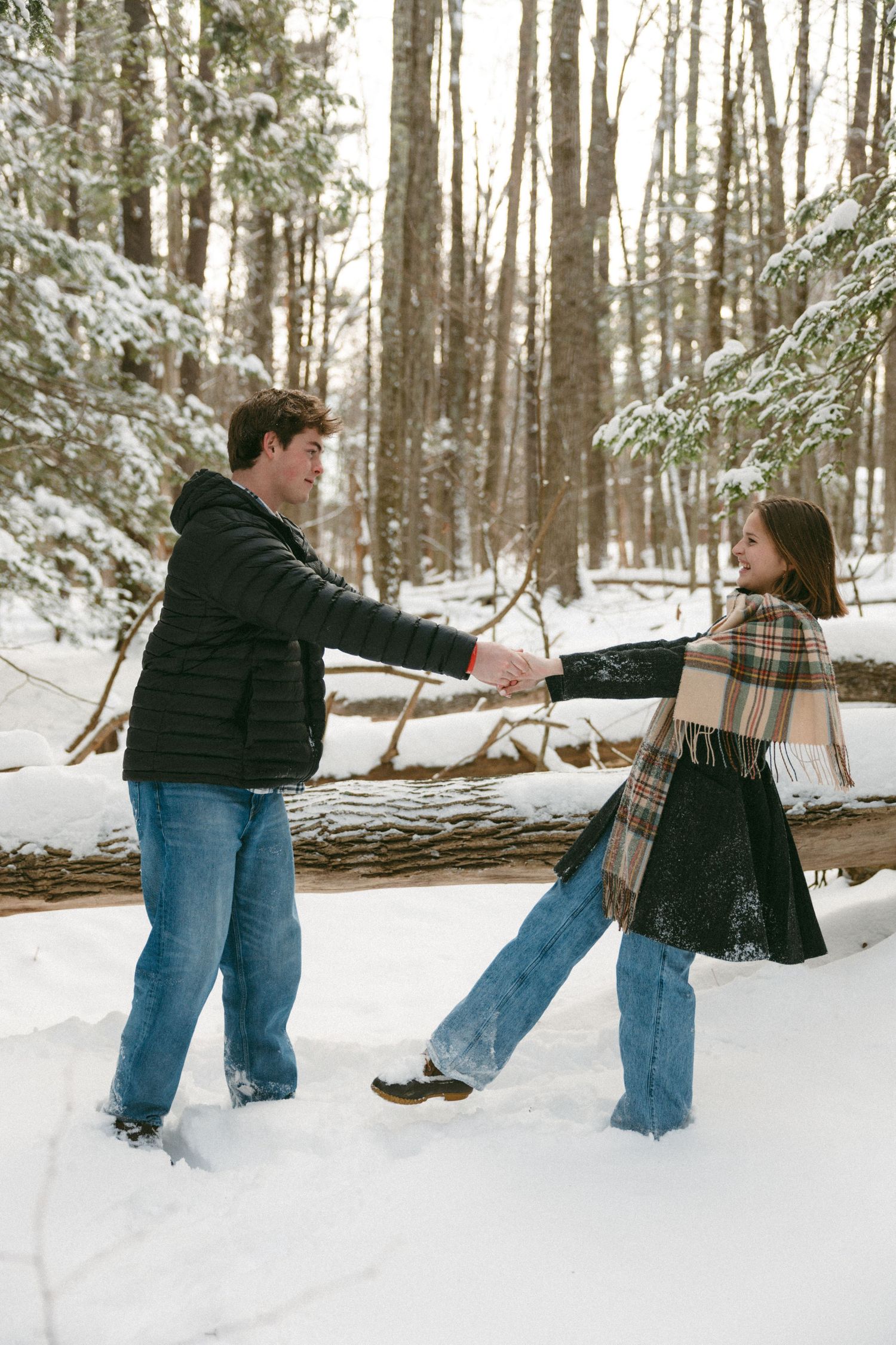 Playful couple having fun in a snowy winter forest, falling together in a sequence of romantic moments.