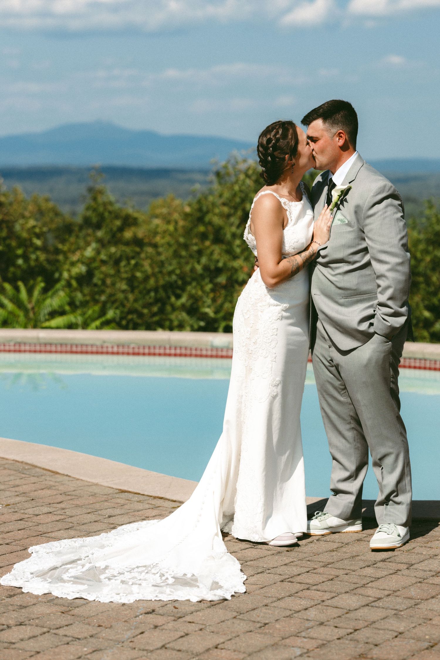 Wedding couple sharing intimate moments by infinity pool with mountain views.