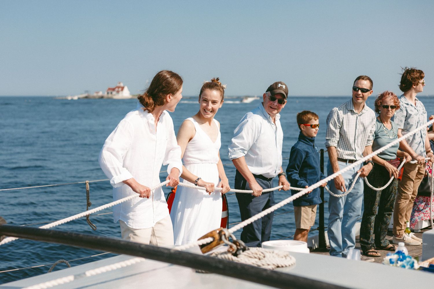 Guests line up along a wooden pier overlooking the ocean during a waterfront event.