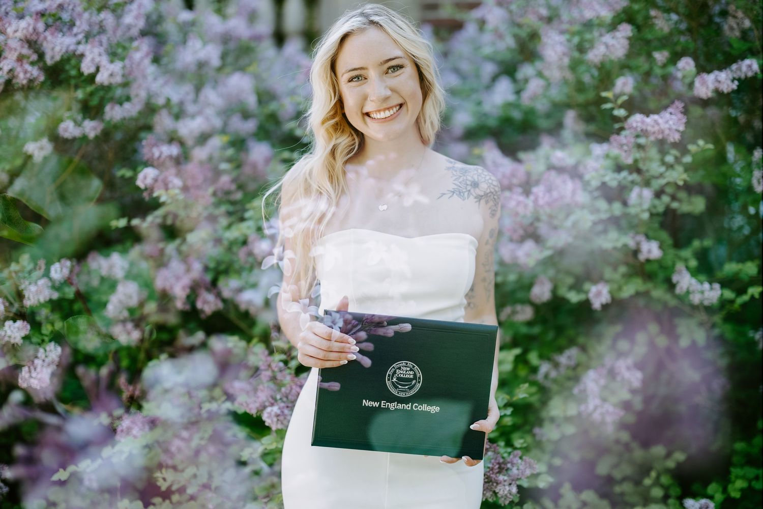 Spring graduate portrait session with cherry blossoms and a laptop in an outdoor garden setting.