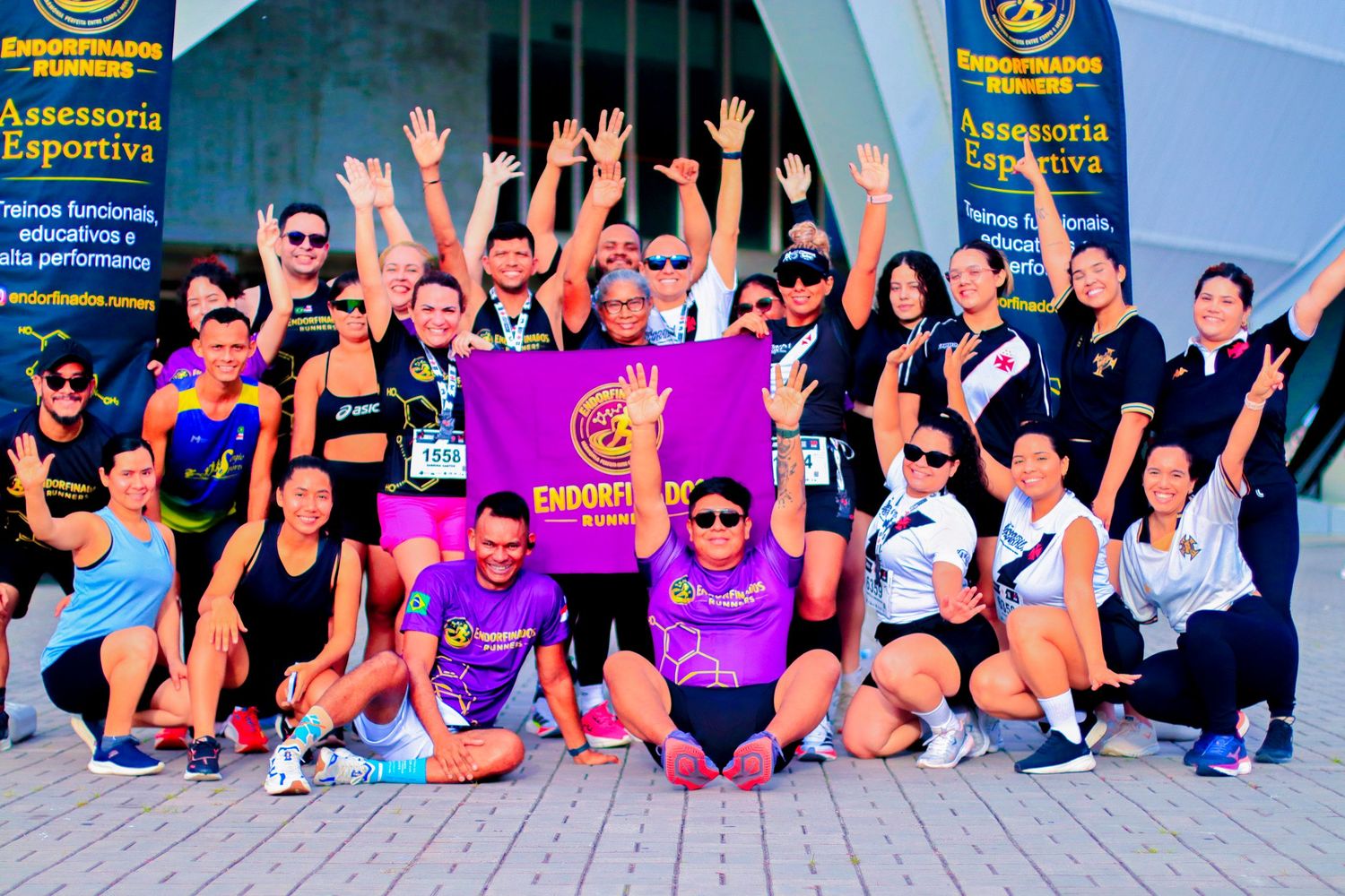 Large running group poses energetically outside Endorfinados Assessoria Esportiva sports coaching facility.