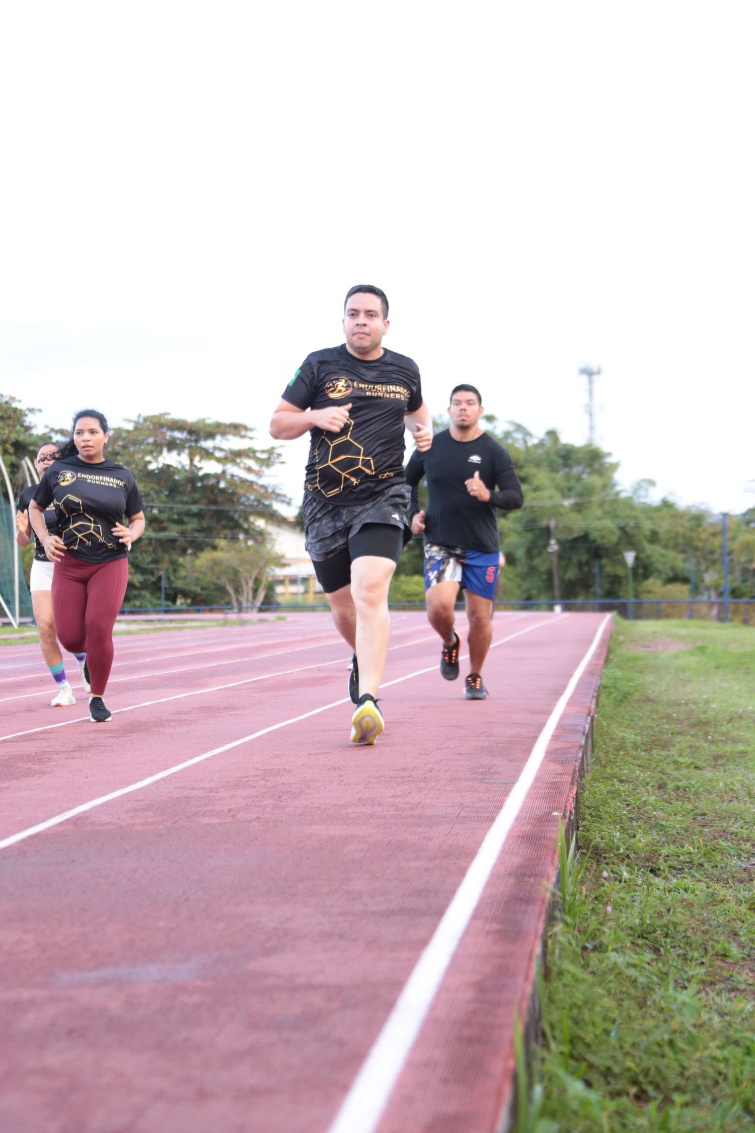 Group of runners training on a red athletic track during outdoor fitness session.