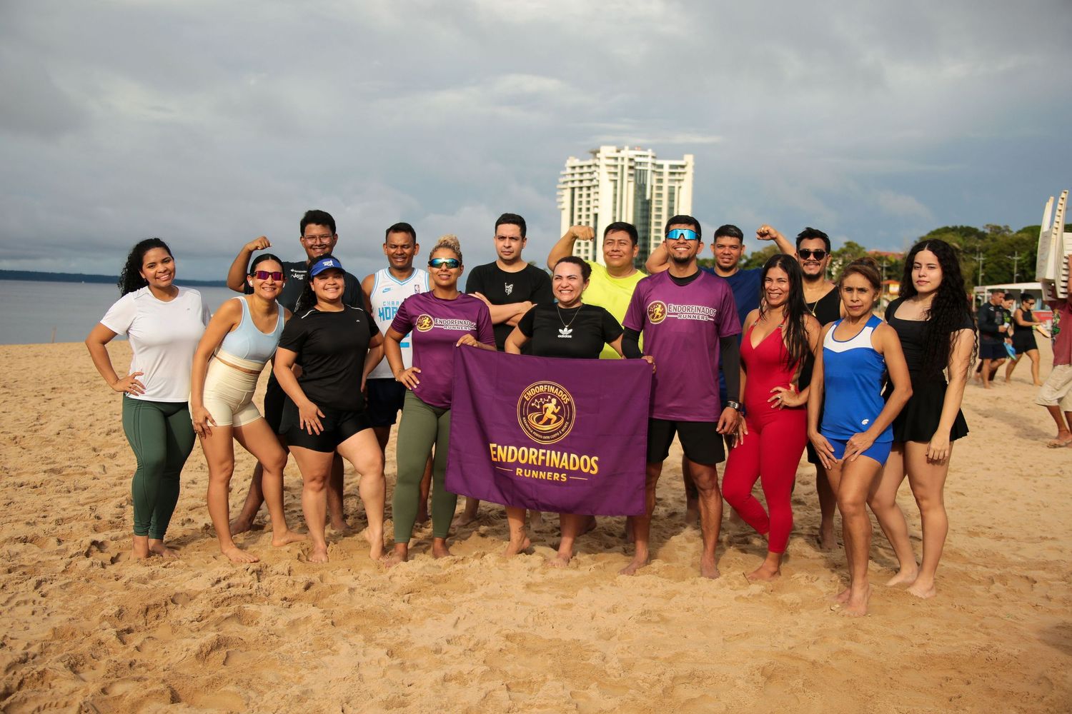 Endorfinados Runners group poses together on sandy beach holding purple team banner.