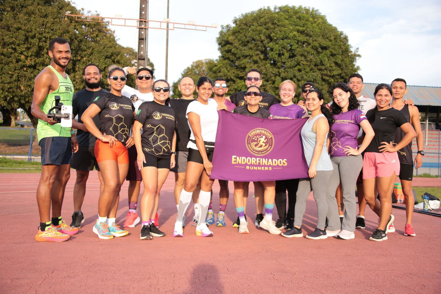 Group of runners posing on a track holding an Endorfinados banner after a training session.
