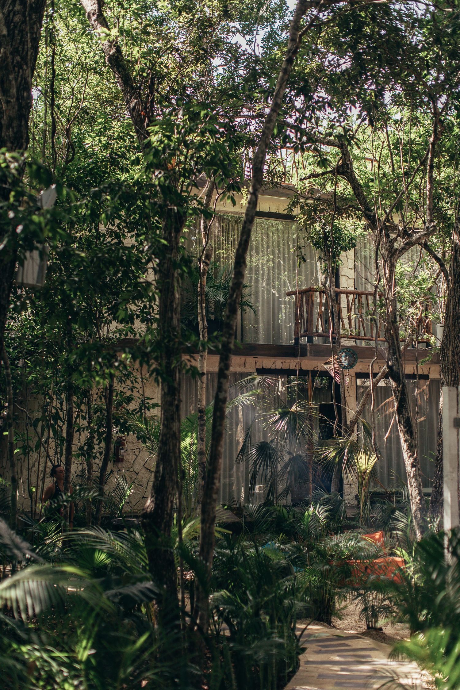A lush jungle treehouse with wooden balcony surrounded by tropical trees and dense green foliage in a serene forest setting.