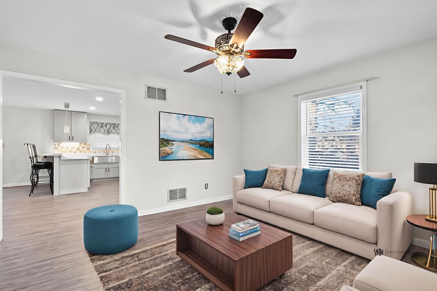 Modern apartment interior with white walls, ceiling fan, and hardwood floors showcasing multiple connected living spaces.