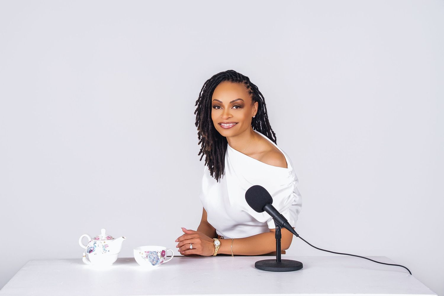Woman in black outfit speaking into microphone during interview or podcast recording session.