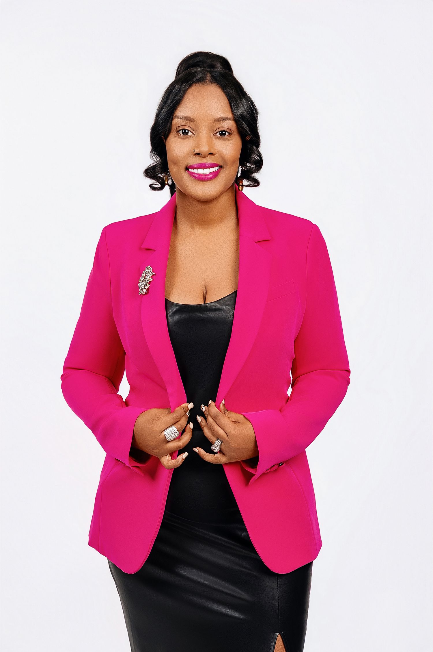 Professional portrait of someone wearing a vibrant hot pink blazer over a black dress against a white background.