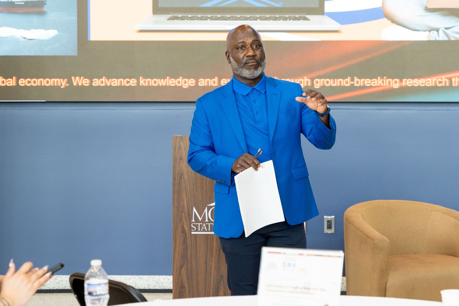 A series of six connected photos showing someone in blue presenting and gesturing during a professional presentation.
