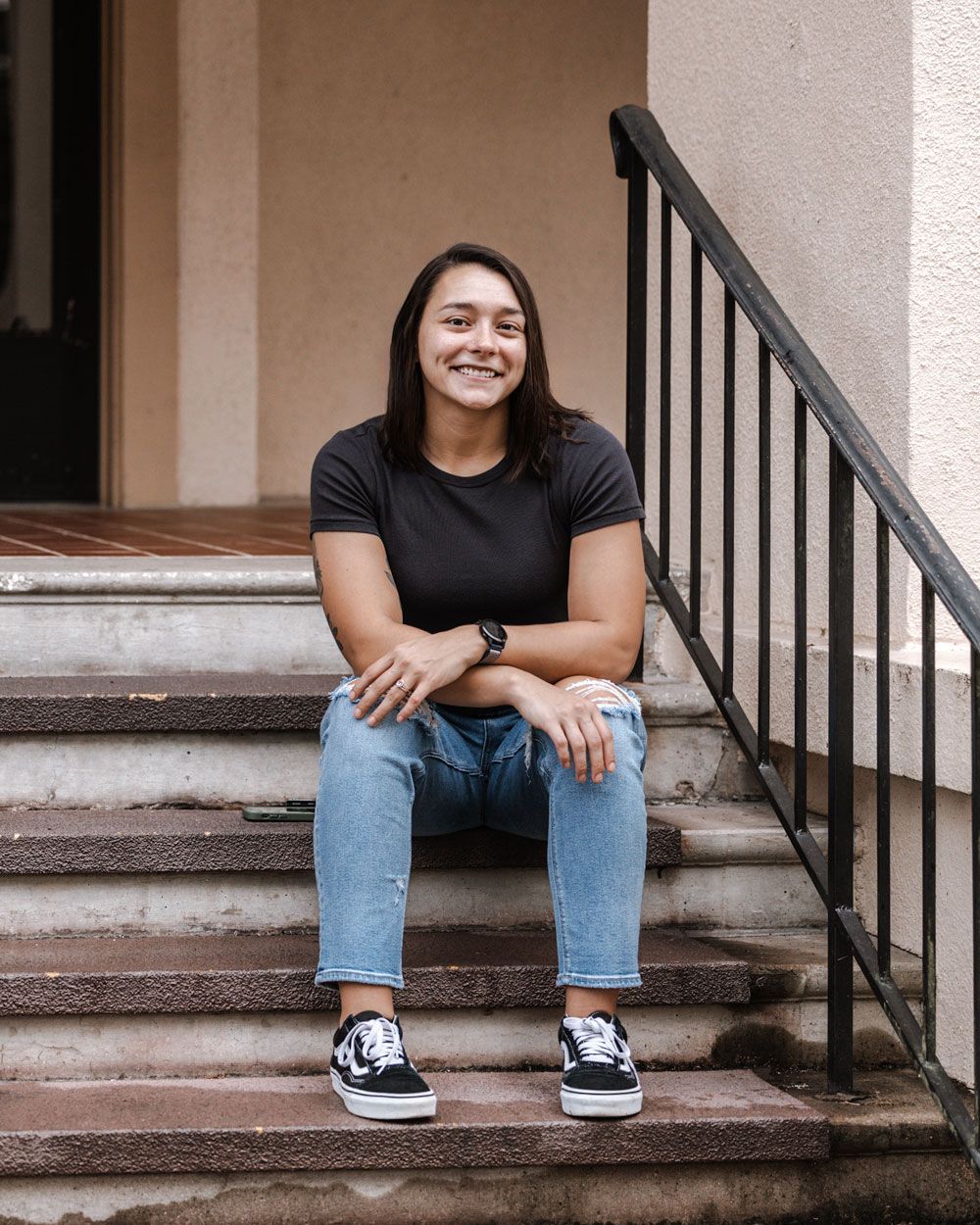Photo of woman sitting on stairs with black short sleeve shirt and jeans